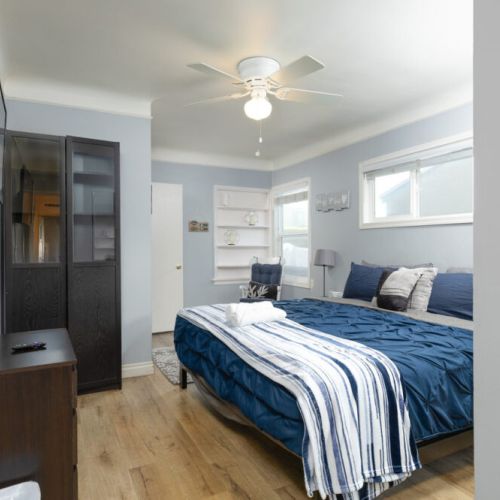 Master bedroom furnished with king-sized bed, plenty of storage, and a mirrored sliding closet
