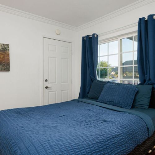 Second bedroom furnished with a queen-sized bed, closet, and attached bathroom.