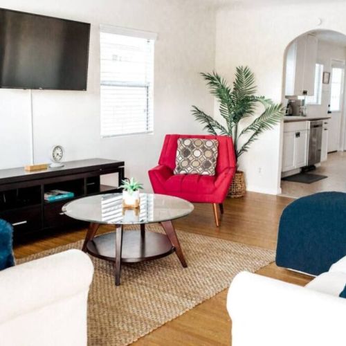 Living room equipped with Smart 4K TV, games, and a peek into the kitchen.