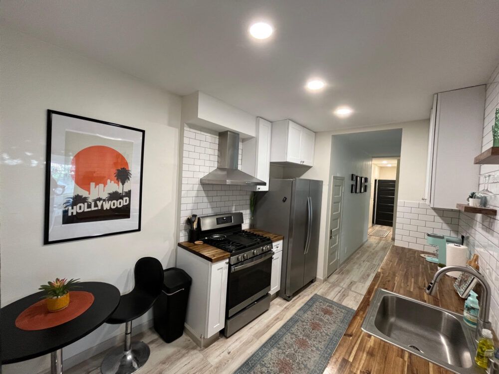 Fully-stocked kitchen furnished with stainless steel appliances and cookingware.