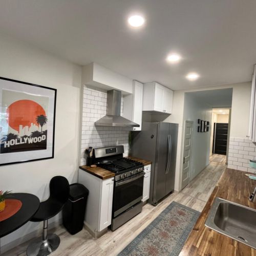 Fully-stocked kitchen furnished with stainless steel appliances and cookingware.