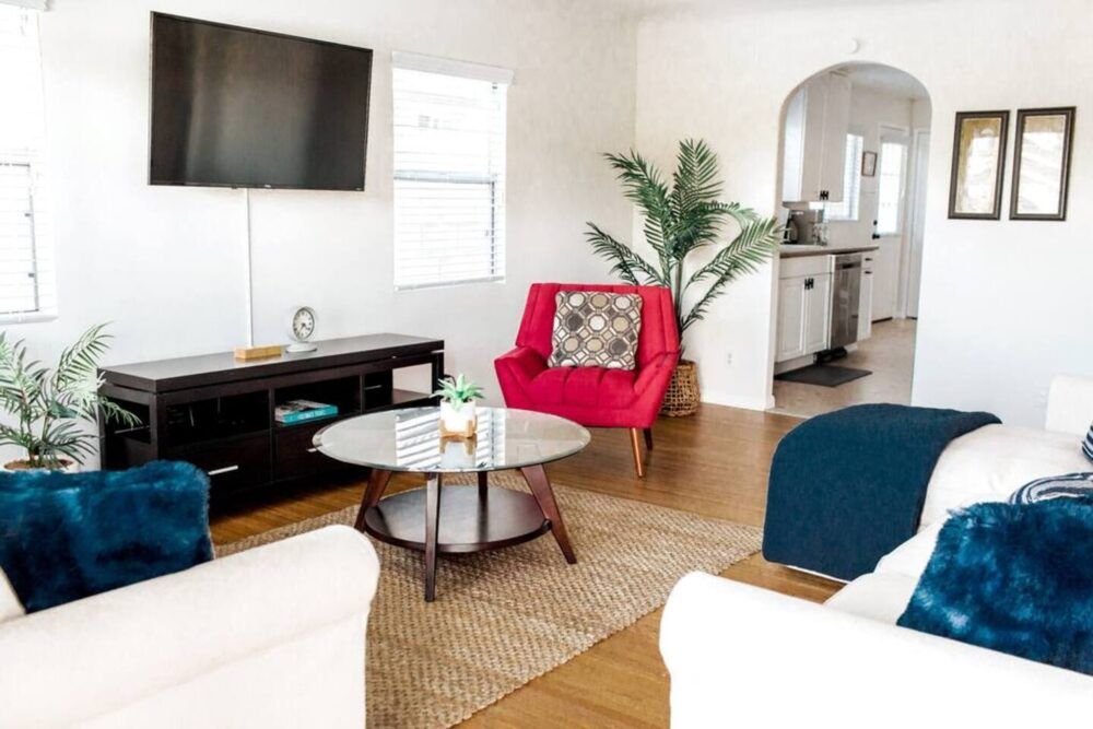 Living room equipped with Smart 4K TV, games, and a peek into the kitchen.