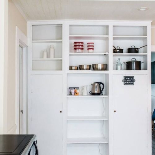Kitchen views. Iron + ironing board, cleaning supplies, and heaters are stored in cabinets.