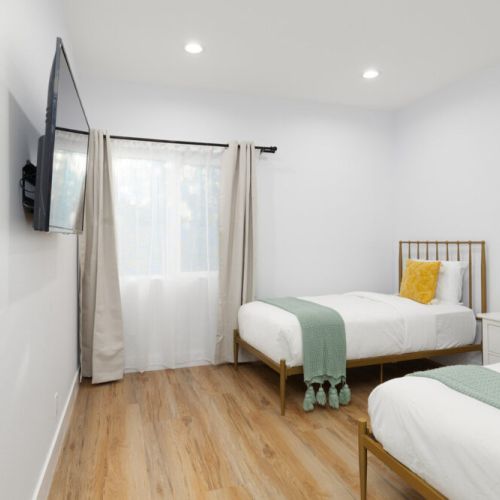 Third bedroom furnished with two twin-sized beds, a Smart TV, and full-sized closet.