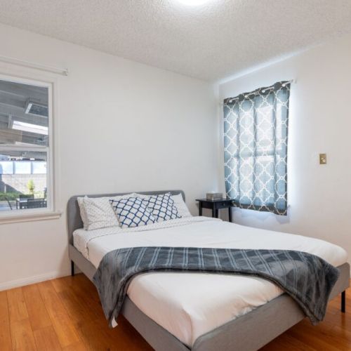 Downstairs bedroom furnished with a queen-sized bed, a full-sized closet, and nightstand.